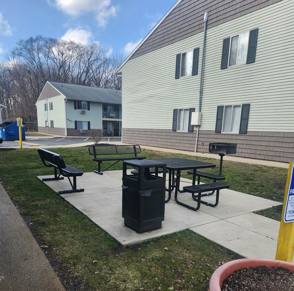 a picnic table and a trash can in front of a building