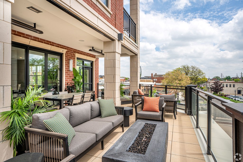 A patio with a couch, chairs, and a table with a potted plant on it.