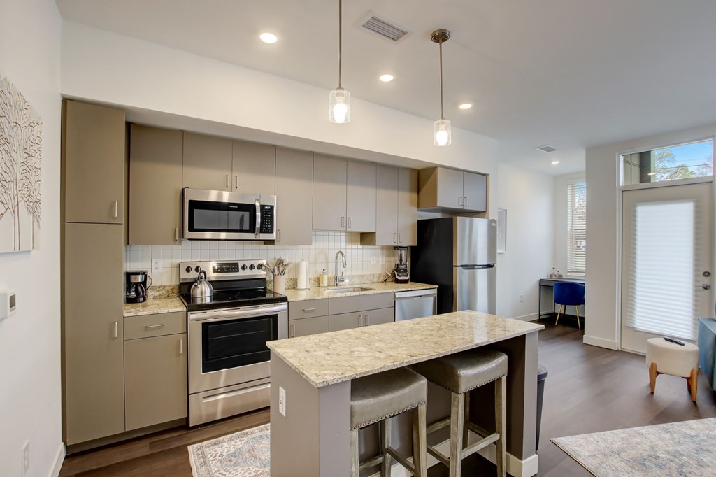 A modern kitchen with a large island and stools.