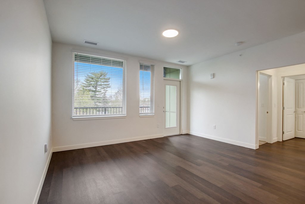 an empty living room with wood floors and a window