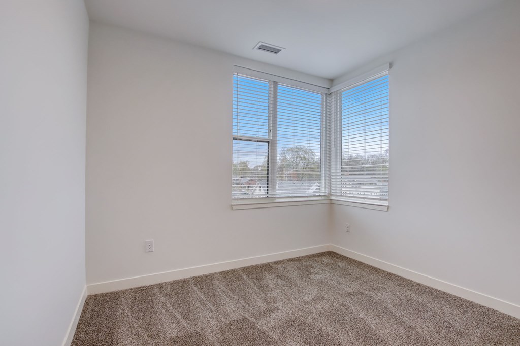 A room with a carpeted floor and a window with blinds.