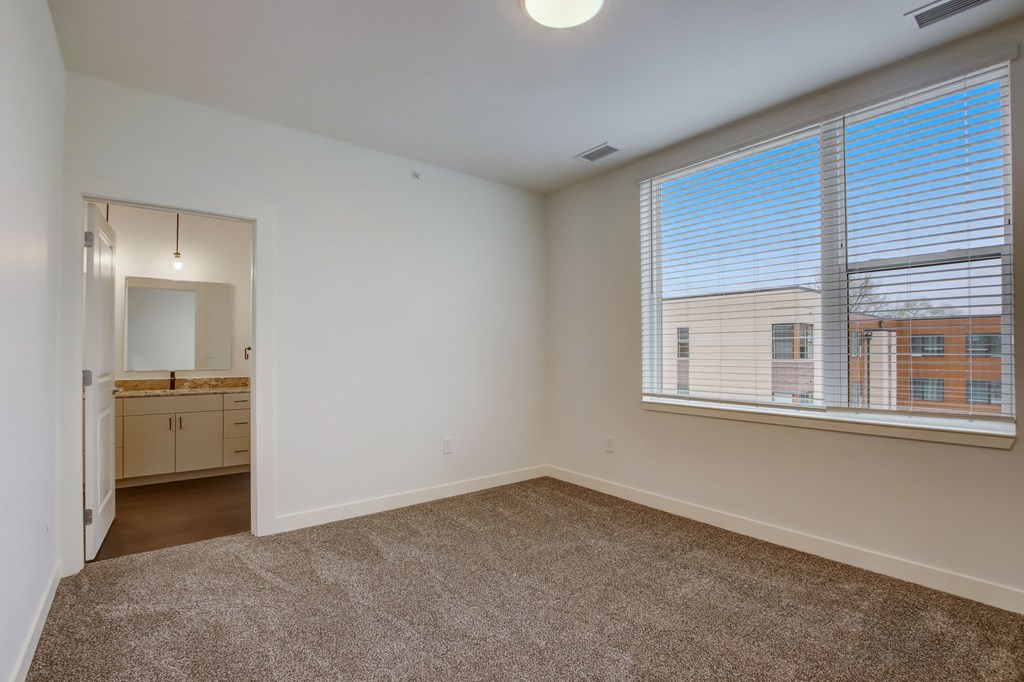 A room with a carpeted floor and a window with blinds.