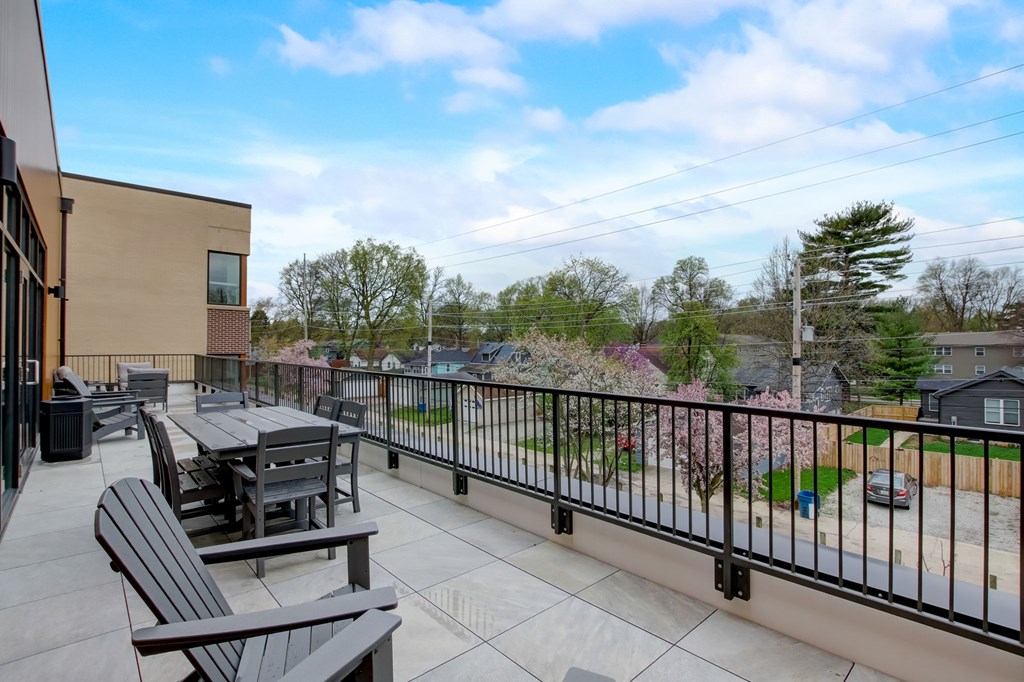 A patio with a table and chairs overlooks a residential area.