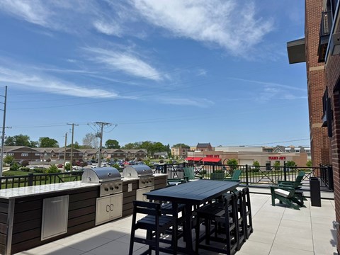 A rooftop patio with a black table and chairs.