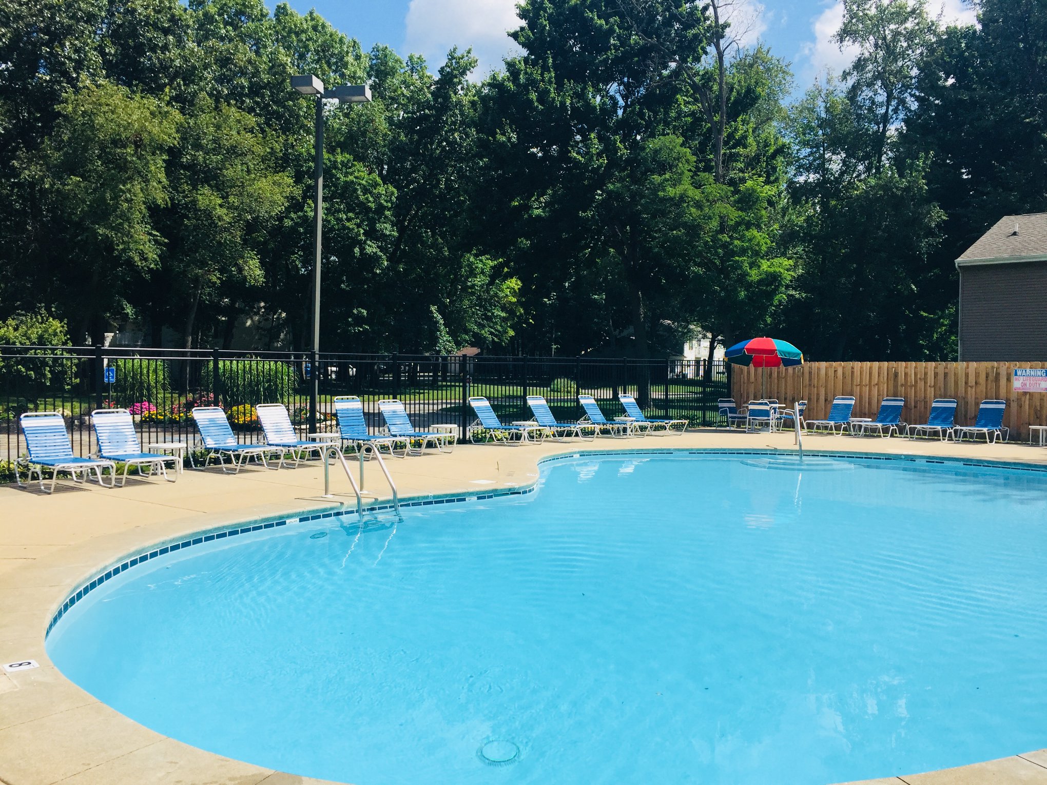 a large pool with chairs and a fence around it