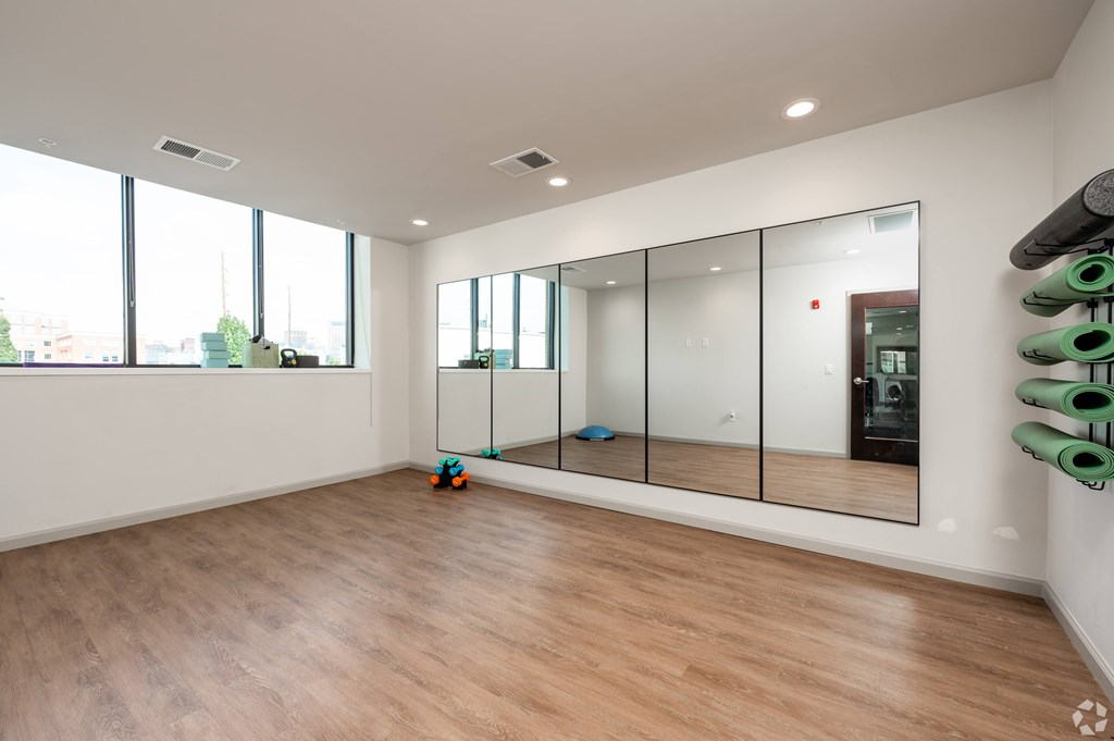 A room with a large mirror and wooden flooring.