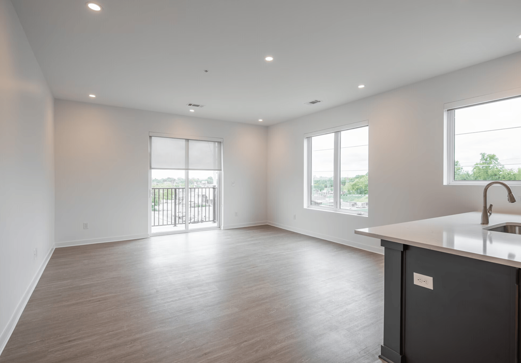 A spacious kitchen and living room with a wooden floor and white walls.