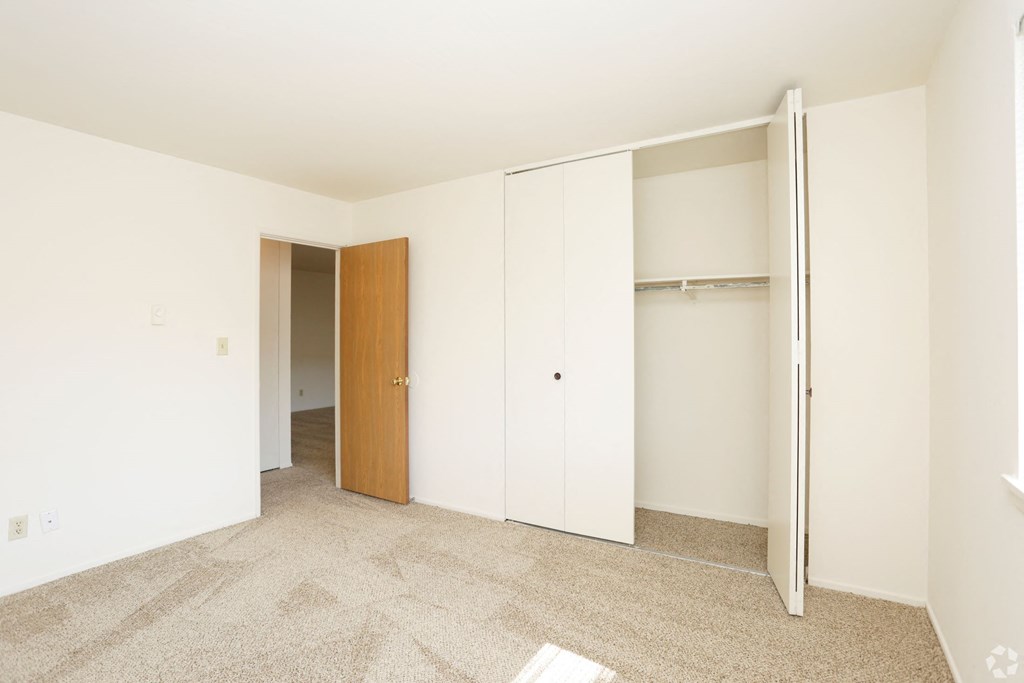 a bedroom with white walls and a closet with a door