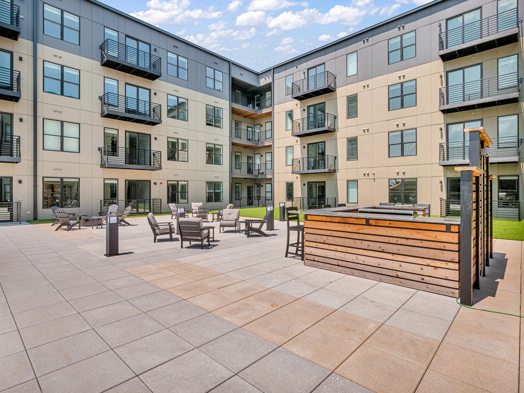 an exterior view of an apartment building during the day with tables and chairs