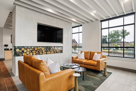 A living room with a tan couch and a flat screen TV mounted on the wall.