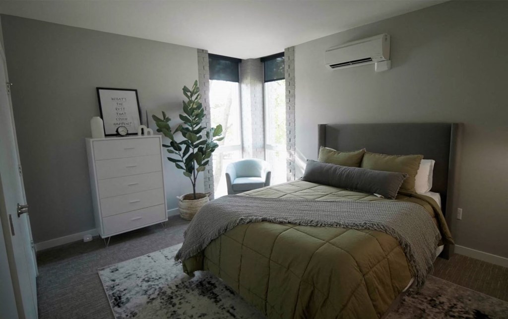 model bedroom with green bedding and a dresser