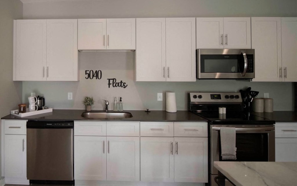 view of a kitchen with white cabinets and stainless steel appliances