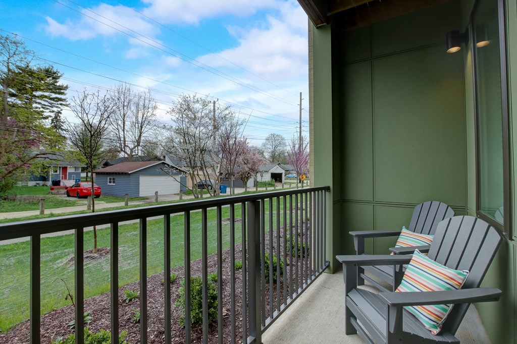 a balcony with two chairs and a view of a yard and houses