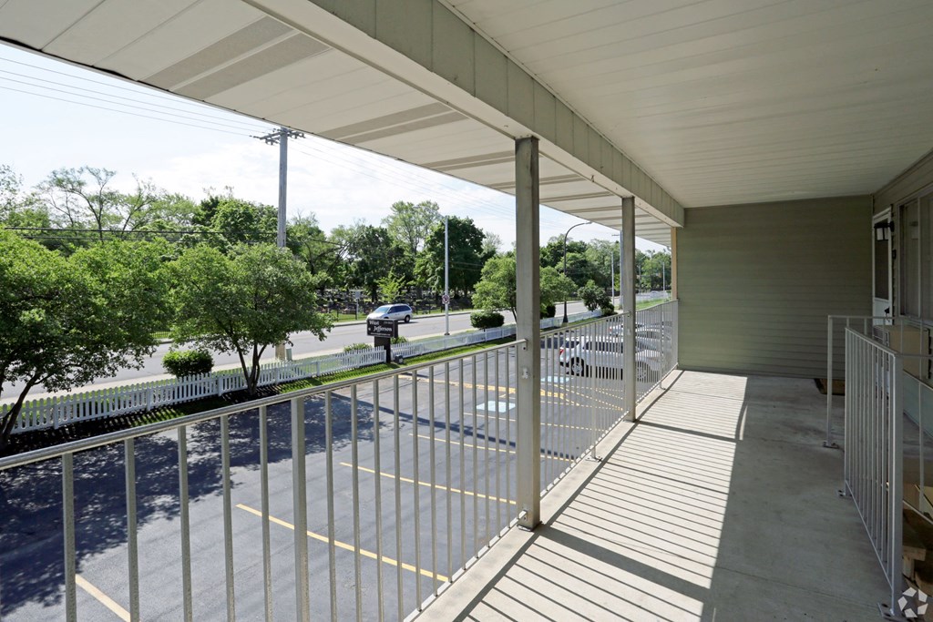the view from the porch of a building with white metal railings