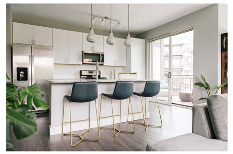 a kitchen with white cabinets and a bar with blue chairs