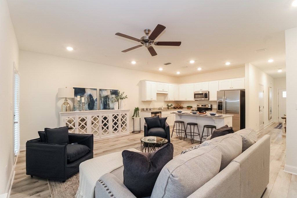 the living room and kitchen in a new home with a ceiling fan