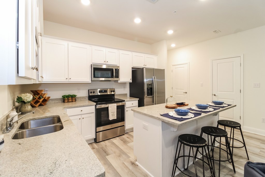 a large kitchen with white cabinets and stainless steel appliances