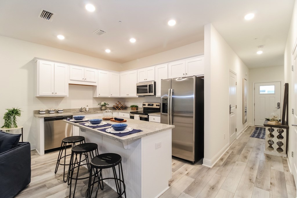 a large kitchen with stainless steel appliances and a bar with three stools