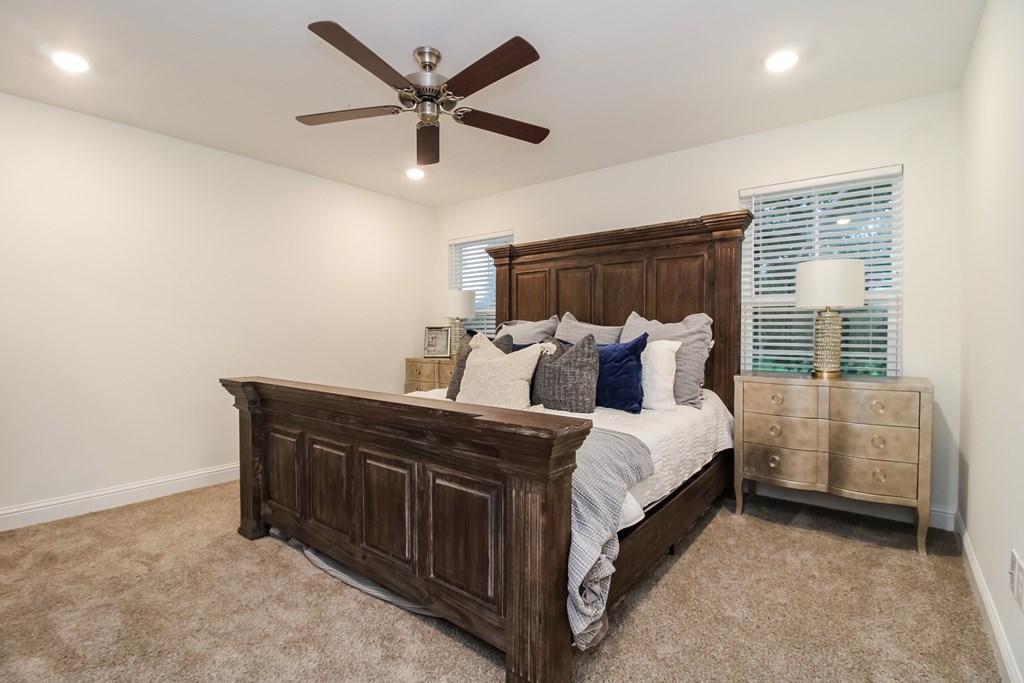 the master bedroom has a large bed and a ceiling fan