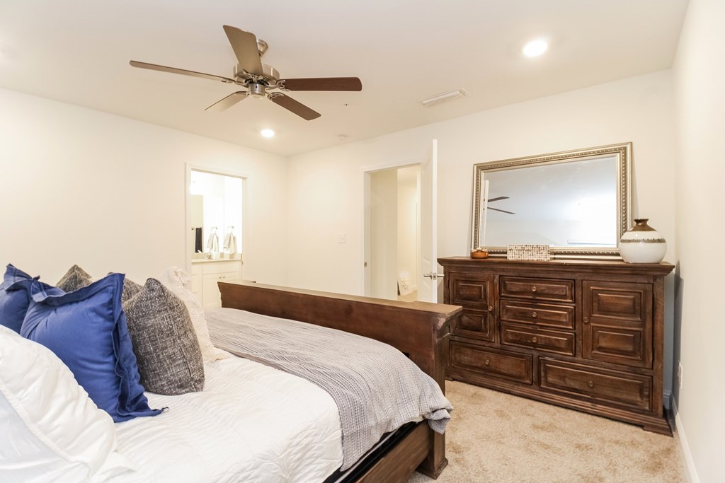 a bedroom with a bed and a dresser and a ceiling fan