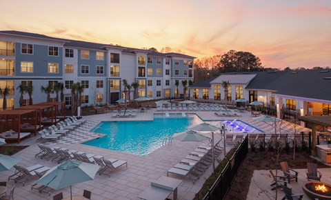 A large outdoor swimming pool surrounded by lounge chairs and umbrellas.