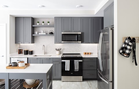 A modern kitchen with a refrigerator on the right and a sink in the middle.