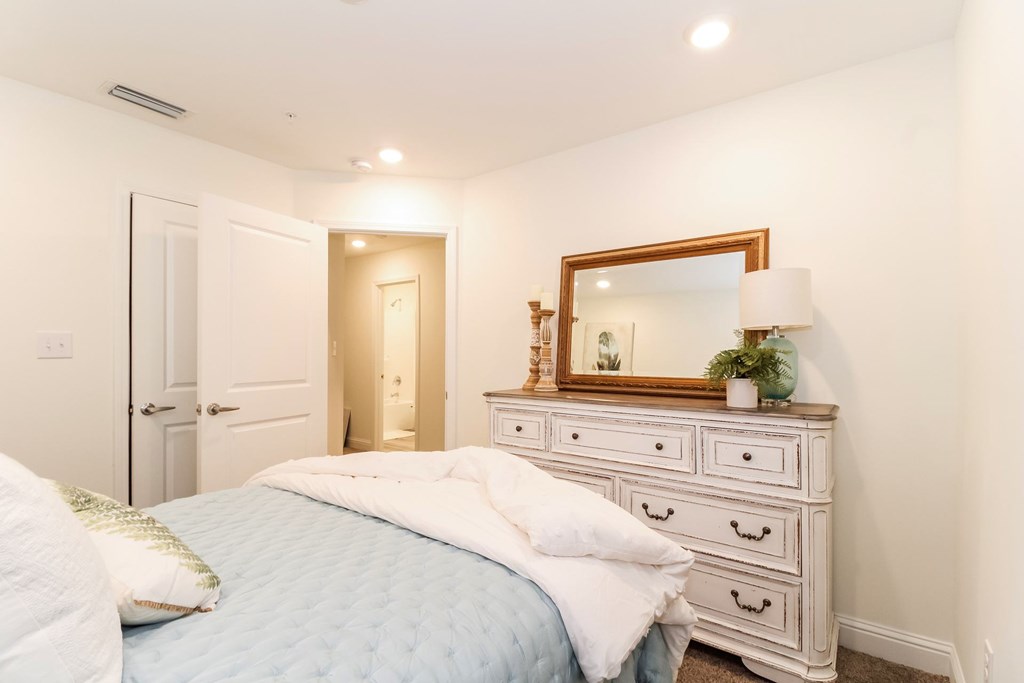 a bedroom with a bed and a dresser with a mirror