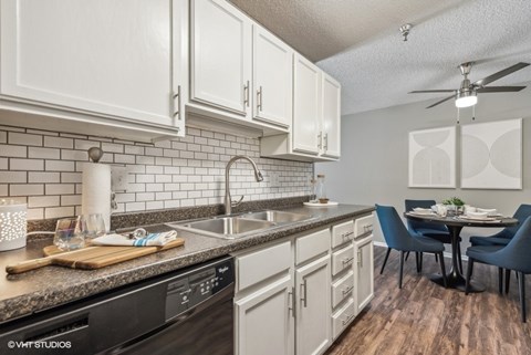 A kitchen with a black dishwasher and white cabinets.