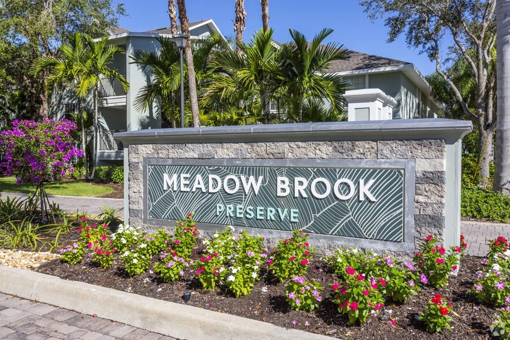 a sign for meadow brook preserve in front of plants and flowers