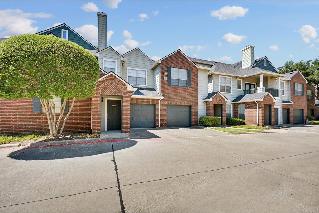 an empty parking lot in front of a brick house