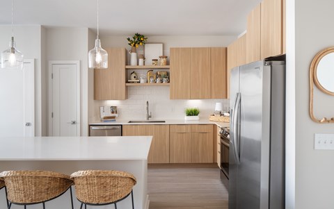 A modern kitchen with a white countertop and wooden cabinets.
