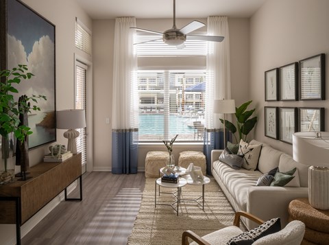 A living room with a large window, a sofa, a coffee table, and a painting on the wall.