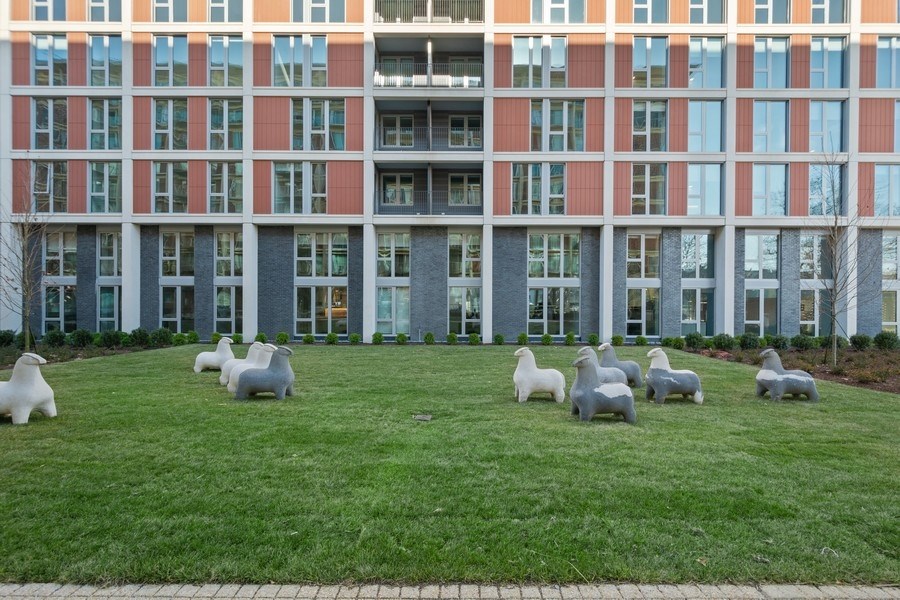 a sculpture of sheep in the grass in front of a building