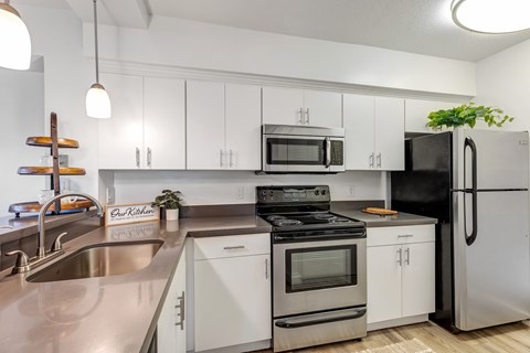 an apartment kitchen with stainless steel appliances and white cabinets