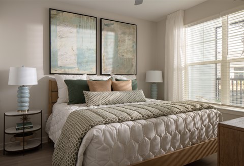A bedroom with a large bed and two lamps.