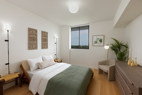 A bedroom with a large bed and a window overlooking the ocean.
