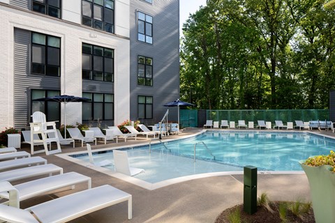 a swimming pool with chairs and umbrellas in front of a building