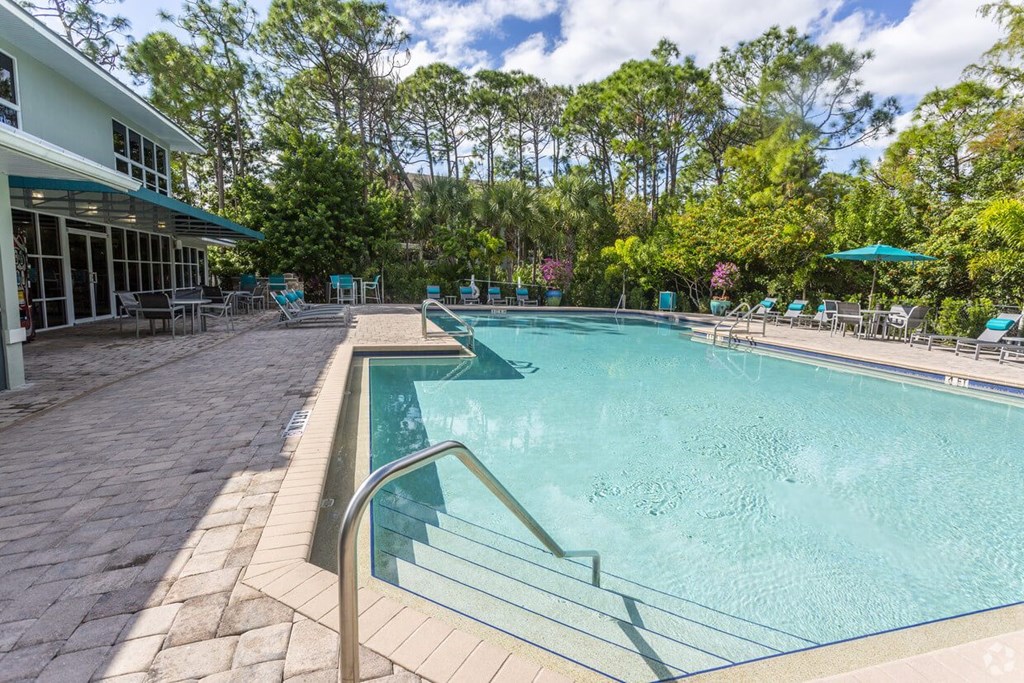a swimming pool with a building and trees in the background