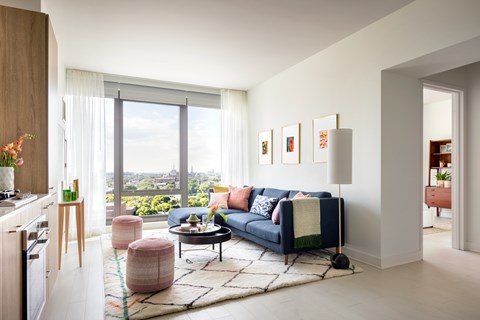A living room with a blue couch and a large window overlooking the city.