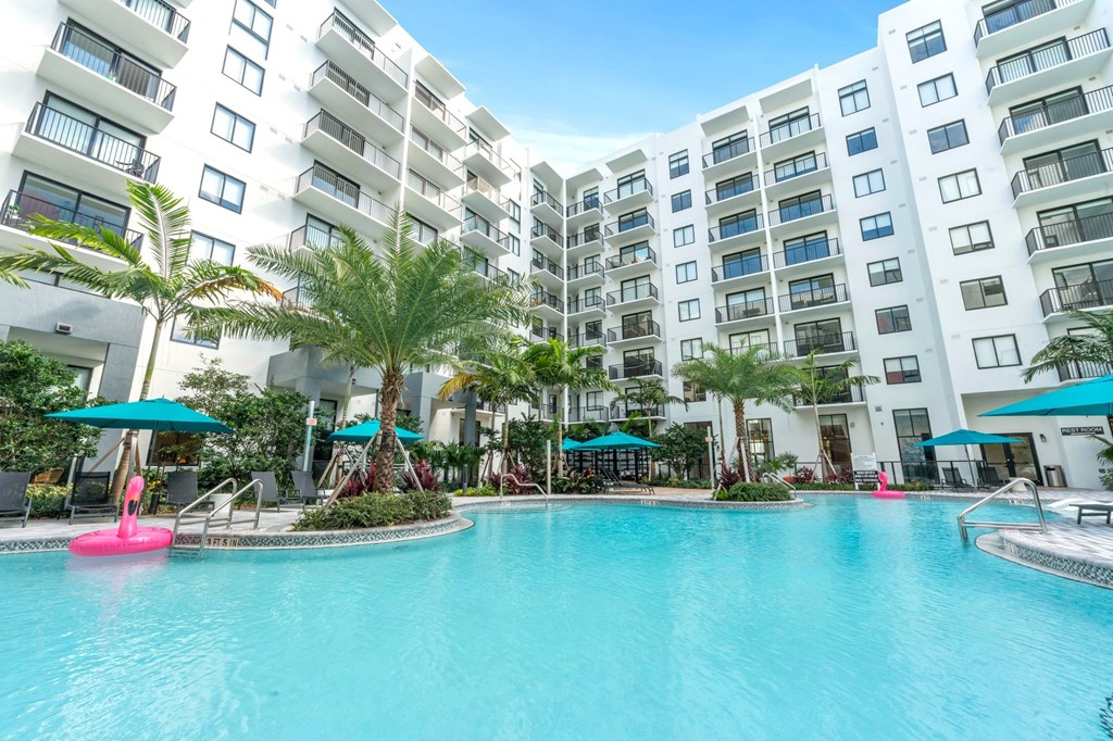A large swimming pool in front of a white apartment building.