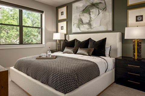 A bedroom with a large bed and a painting on the wall.