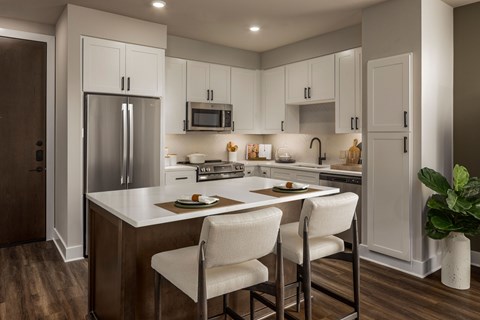 A kitchen with white cabinets and a wooden floor.
