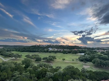 an aerial view of a golf course with a sunset in the background