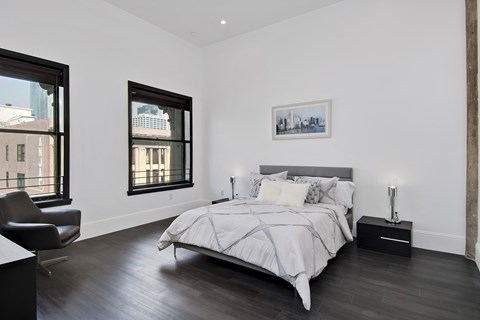 A bedroom with a large bed and a chair.