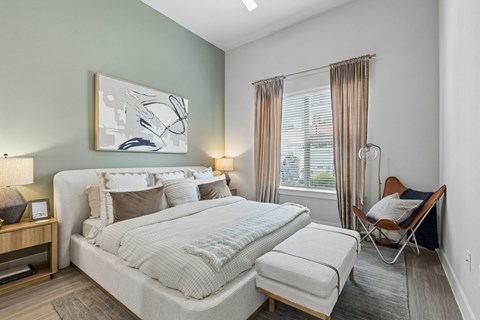 A bedroom with a large bed and a chair.
