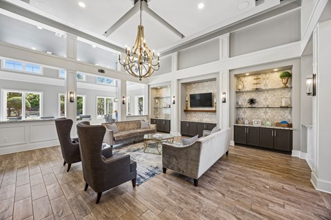A living room with a grey sofa and a chandelier.
