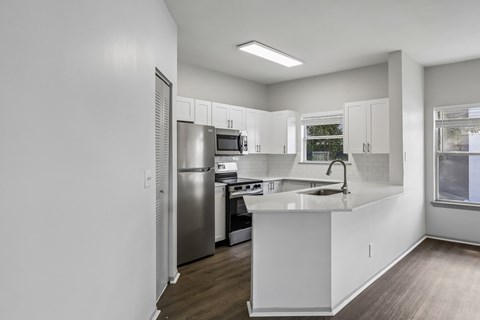 A kitchen with white cabinets and a stainless steel refrigerator.