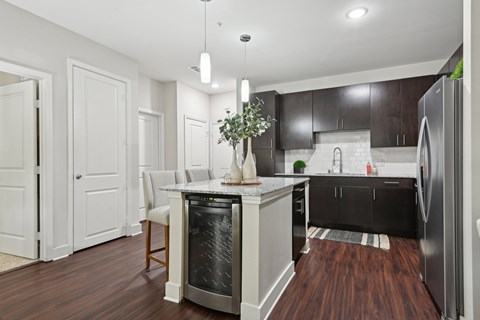A modern kitchen with dark wood floors and white walls.