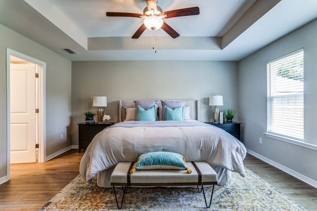 the master bedroom has a large bed and a ceiling fan