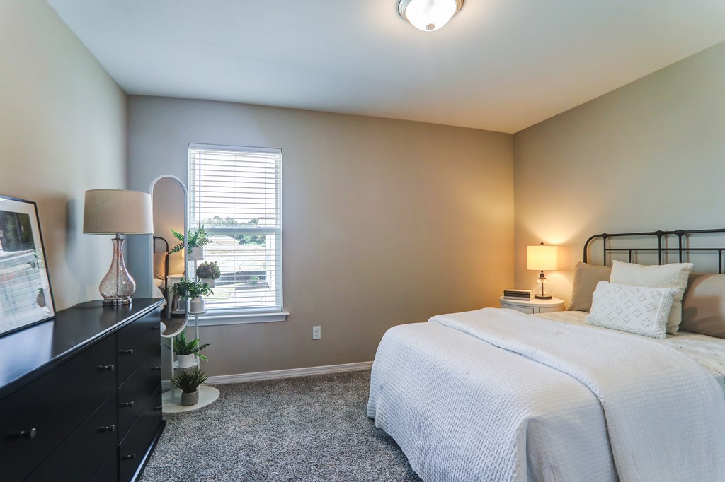 a bedroom with a bed and a dresser and a window